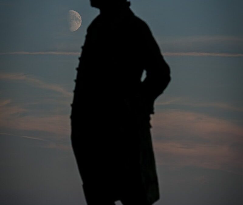 Silhouette of a man against a twilight sky with moon.
